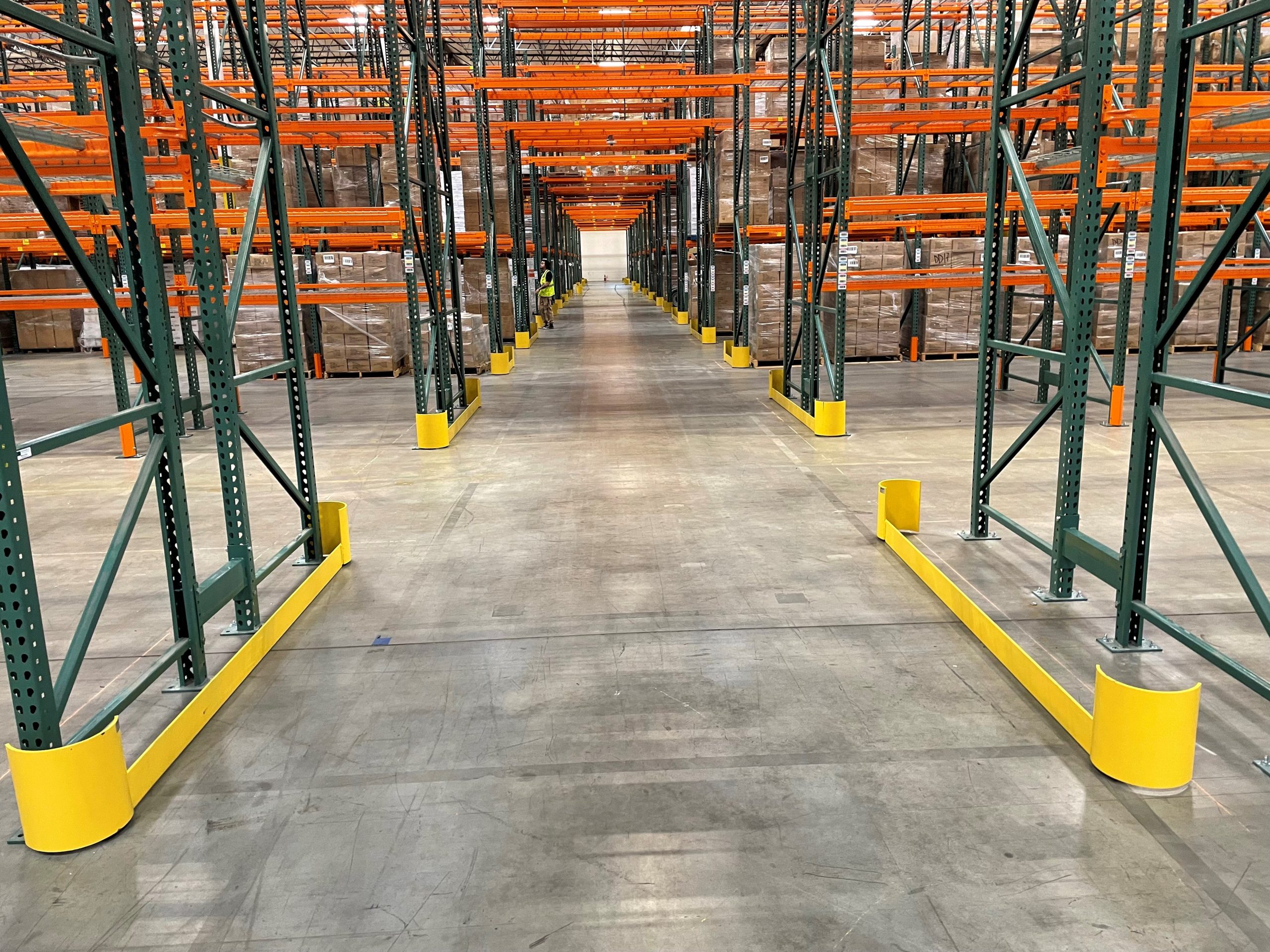View down a warehouse aisle showing tunnel bays and yellow safety guards